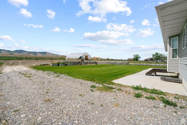 18605 N 6000 W, Riverside, UT 84334 - view of green lawn with a playground, a mountain view, and a patio area