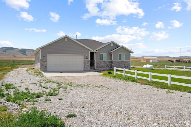 18605 N 6000 W, Riverside, UT 84334 - single story home with driveway, a garage, stone siding, and a mountain view