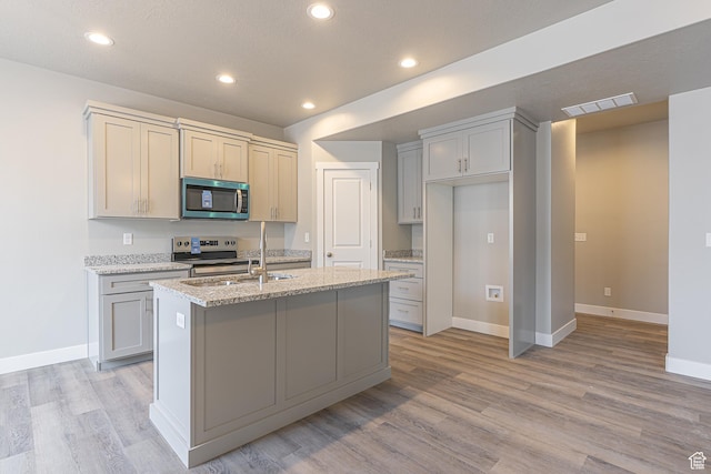 2202 S 1120 W Unit 64, Nibley, UT 84321 - kitchen with stainless steel appliances, light wood-style floors, an island with sink, light stone counters, and recessed lighting