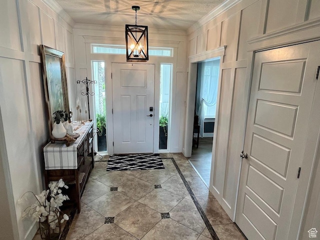 4053 W 3770 S, Wellsville, UT 84339 - foyer entrance featuring inlaid floor details, a decorative wall, light tile patterned flooring, and crown molding