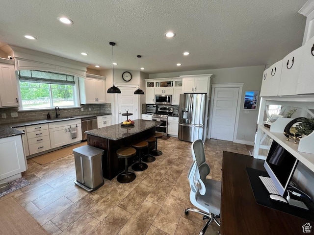 4053 W 3770 S, Wellsville, UT 84339 - kitchen featuring appliances with stainless steel finishes, decorative backsplash, a kitchen breakfast bar, a center island, and a textured ceiling