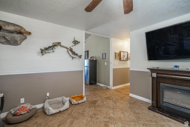 737 Carma Way, Washington, UT 84780 - living room with a ceiling fan, a textured ceiling, light tile patterned floors, and a glass covered fireplace