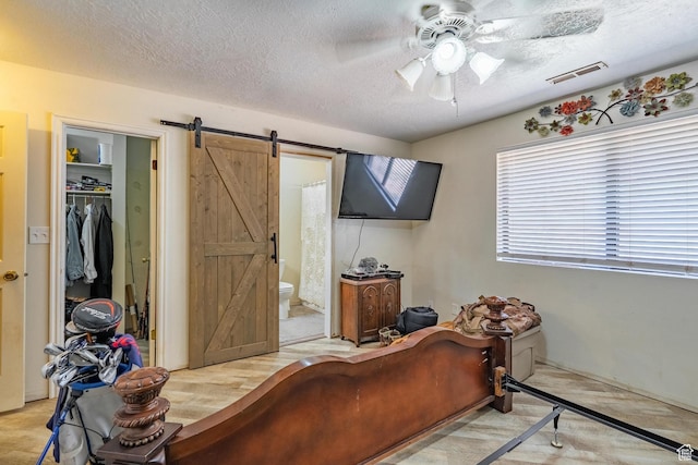 737 Carma Way, Washington, UT 84780 - bedroom with a barn door, a textured ceiling, ensuite bath, a spacious closet, and a ceiling fan