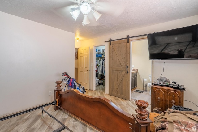 737 Carma Way, Washington, UT 84780 - bedroom with a barn door, a spacious closet, light wood finished floors, a textured ceiling, and ensuite bath