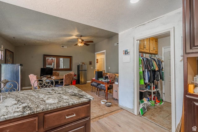 737 Carma Way, Washington, UT 84780 - kitchen featuring freestanding refrigerator, ceiling fan, a textured ceiling, light stone counters, and light wood finished floors