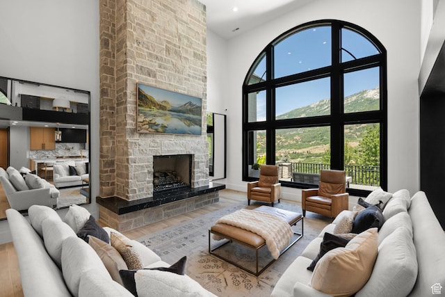 1643 E Box Elder Dr, Alpine, UT 84004 - living room featuring a towering ceiling, wood finished floors, a stone fireplace, healthy amount of natural light, and recessed lighting