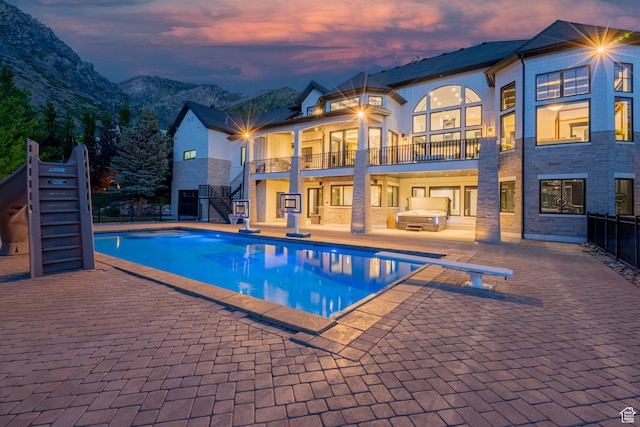 1643 E Box Elder Dr, Alpine, UT 84004 - pool at dusk featuring stairs, a diving board, an outdoor pool, and a patio area