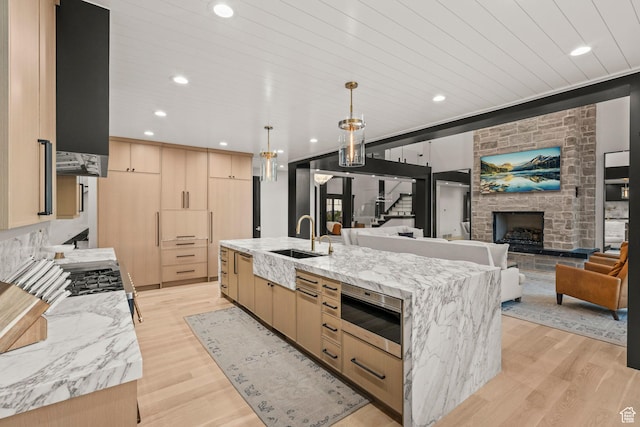 1643 E Box Elder Dr, Alpine, UT 84004 - kitchen with light brown cabinets, a fireplace, light wood finished floors, a spacious island, and light stone countertops
