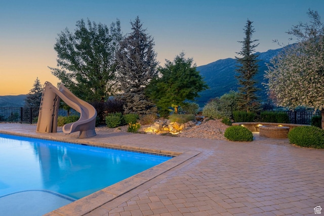 1643 E Box Elder Dr, Alpine, UT 84004 - pool at dusk featuring a mountain view, a water slide, and a patio area