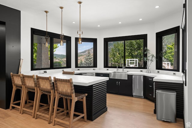 1643 E Box Elder Dr, Alpine, UT 84004 - kitchen with dark cabinetry, light countertops, a breakfast bar area, light wood finished floors, and a peninsula