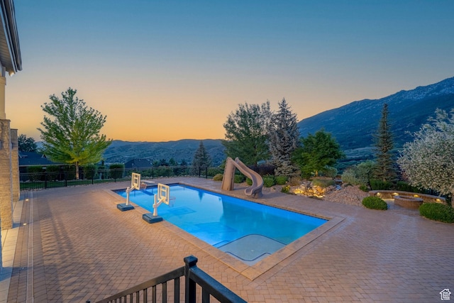 1643 E Box Elder Dr, Alpine, UT 84004 - pool at dusk featuring a water slide, a mountain view, a patio area, and a hot tub