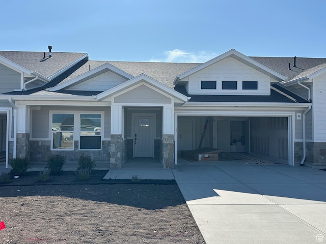 2613 S 2430 W Unit 111, Syracuse, UT 84075 - view of front facade with concrete driveway, stone siding, a shingled roof, and an attached garage