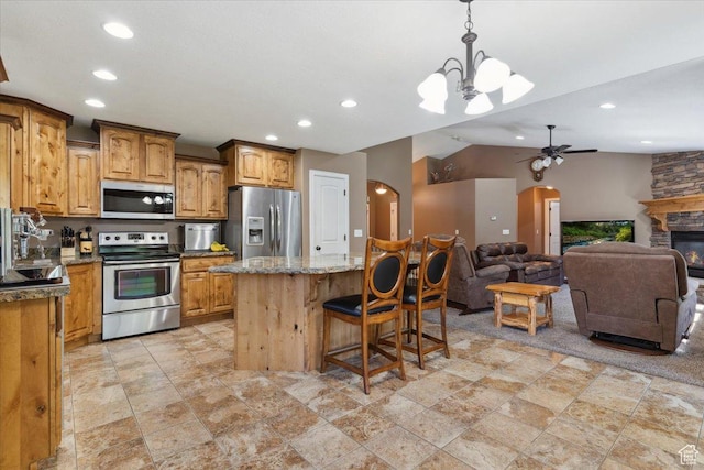 3146 N 750 W, Pleasant View, UT 84414 - kitchen featuring appliances with stainless steel finishes, open floor plan, arched walkways, a kitchen bar, and recessed lighting
