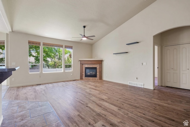 6097 W Cedar Hill Rd S, West Jordan, UT 84081 - unfurnished living room with ceiling fan, vaulted ceiling, wood finished floors, a glass covered fireplace, and arched walkways