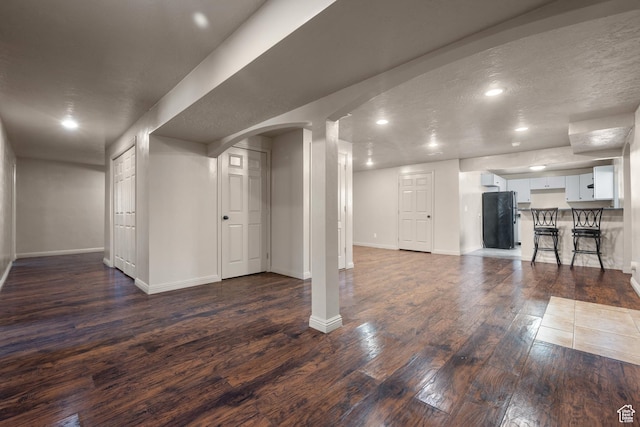 6097 W Cedar Hill Rd S, West Jordan, UT 84081 - basement featuring freestanding refrigerator, arched walkways, dark wood-type flooring, and recessed lighting