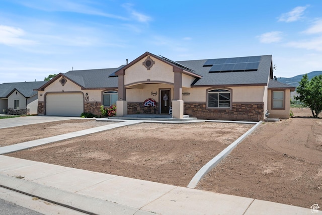 3712 N 250 E, Enoch, UT 84721 - view of front facade with stone siding, stucco siding, roof with shingles, roof mounted solar panels, and driveway