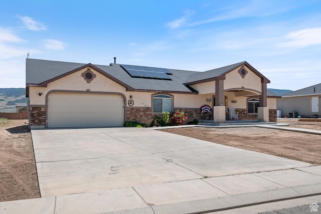 3712 N 250 E, Enoch, UT 84721 - view of front of property with stone siding, stucco siding, solar panels, a garage, and driveway