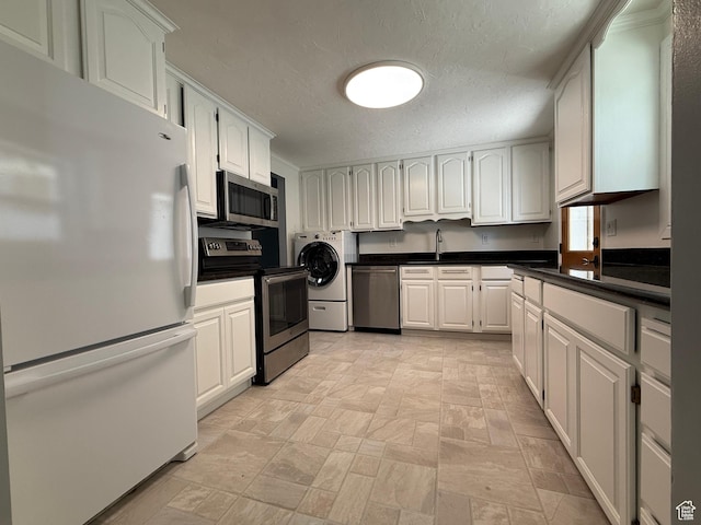 1885 S 50 W, Bountiful, UT 84010 - kitchen with stainless steel appliances, washer / dryer, a textured ceiling, dark countertops, and white cabinetry