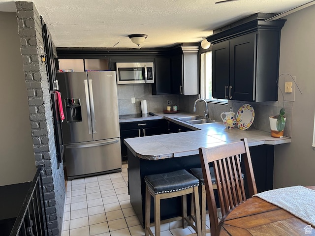 125 E 6940 S, Midvale, UT 84047 - kitchen with appliances with stainless steel finishes, dark cabinetry, backsplash, a breakfast bar area, and a textured ceiling