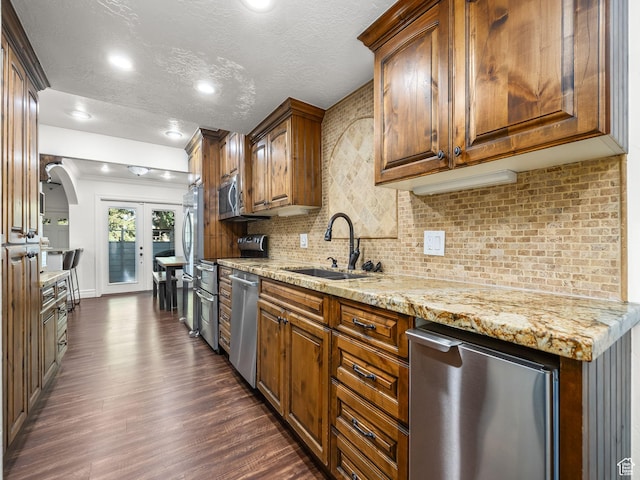 3228 N Brook Ln W, Provo, UT 84604 - kitchen with appliances with stainless steel finishes, dark wood finished floors, light stone counters, decorative backsplash, and a textured ceiling