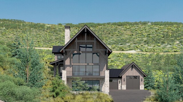 703 S Coyote Tracks Cir, Garden City, UT 84028 - view of front of home featuring a chimney, a balcony, a standing seam roof, and a metal roof