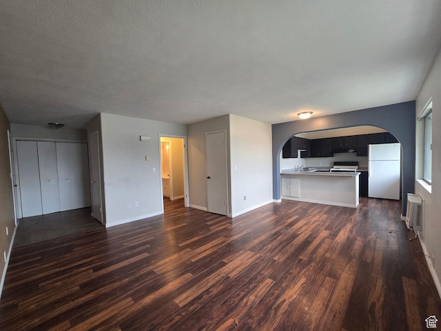 4480 S Atherton Dr Unit 22, Taylorsville, UT 84123 - unfurnished living room with dark wood-style floors, arched walkways, a textured ceiling, and a wall mounted AC