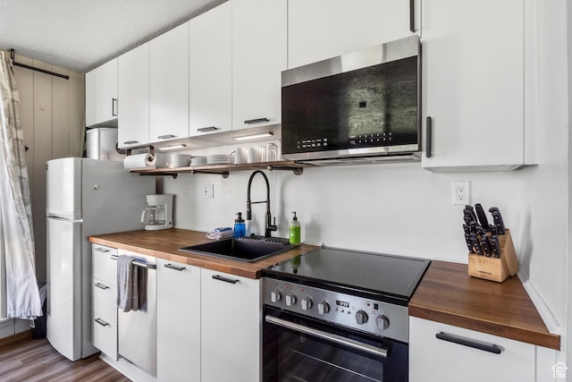 2176 S Bear Blvd # 421, Garden City, UT 84028 - kitchen with wood counters, electric stove, stainless steel microwave, and white cabinets