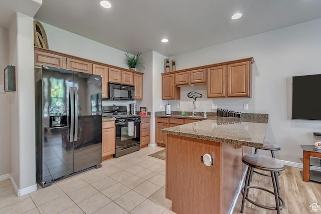 5436 W Brentford Ct, West Valley City, UT 84120 - kitchen with black appliances, a peninsula, a breakfast bar area, stone countertops, and brown cabinets