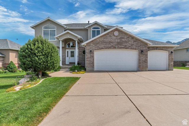 5149 W Rendezvous, Mountain Green, UT 84050 - traditional-style home featuring driveway, a garage, a front yard, stucco siding, and brick siding