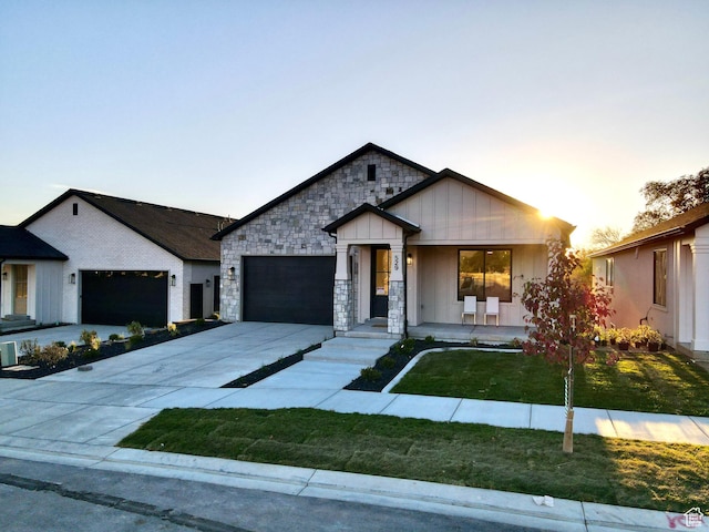 683 N Heritage St, Mapleton, UT 84664 - view of front of home featuring a garage, a lawn, driveway, covered porch, and stone siding