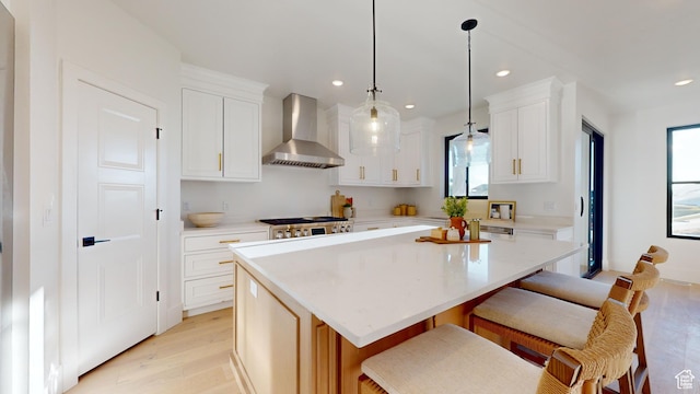 683 N Heritage St, Mapleton, UT 84664 - kitchen featuring wall chimney range hood, light wood-style flooring, light countertops, white cabinets, and a breakfast bar area