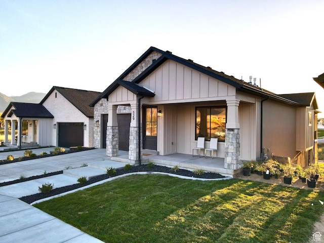683 N Heritage St, Mapleton, UT 84664 - view of front facade with covered porch, a front lawn, stone siding, and board and batten siding