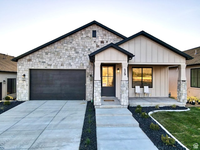 683 N Heritage St, Mapleton, UT 84664 - view of front of house featuring board and batten siding, a garage, concrete driveway, and stone siding