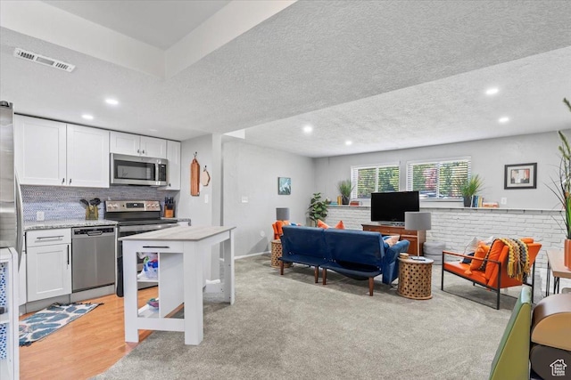 1543 E Spring Run Dr, Salt Lake City, UT 84117 - kitchen with appliances with stainless steel finishes, white cabinetry, a textured ceiling, recessed lighting, and backsplash