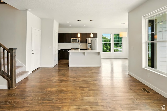 5254 W Burntside Ave, South Jordan, UT 84009 - kitchen featuring appliances with stainless steel finishes, light countertops, dark wood finished floors, a center island with sink, and dark brown cabinets