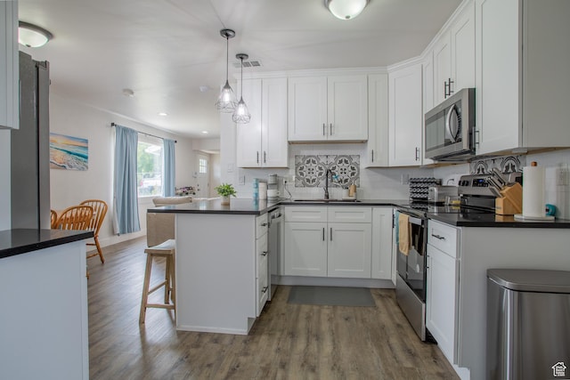 4586 W 4925 S, Kearns, UT 84118 - kitchen featuring stainless steel appliances, wood finished floors, dark countertops, white cabinets, and recessed lighting