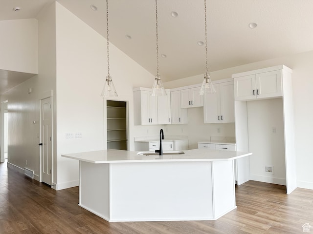 6999 W Hazel Oak Ct, Herriman, UT 84096 - kitchen featuring high vaulted ceiling, wood finished floors, white cabinets, an island with sink, and light countertops