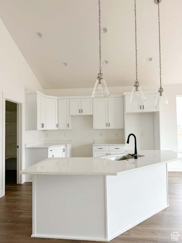 6999 W Hazel Oak Ct, Herriman, UT 84096 - kitchen with vaulted ceiling, a large island, dark wood finished floors, white cabinets, and decorative light fixtures