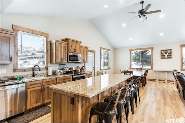 2915 S Golf Course Dr, Garden City, UT 84028 - kitchen with stainless steel appliances, a breakfast bar area, a center island, lofted ceiling, and light stone counters