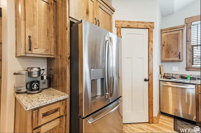 2915 S Golf Course Dr, Garden City, UT 84028 - kitchen with stainless steel appliances, light wood finished floors, light stone countertops, and brown cabinetry