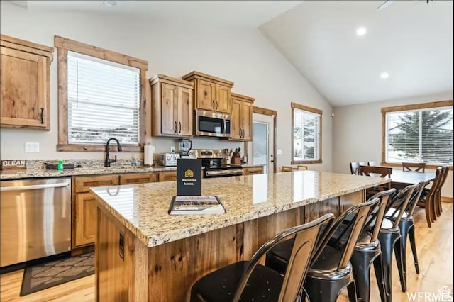 2915 S Golf Course Dr, Garden City, UT 84028 - kitchen with stainless steel appliances, light wood finished floors, vaulted ceiling, a kitchen island, and healthy amount of natural light