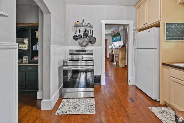 331 Chateau Thierry St, Soda Springs, ID 83276 - kitchen with freestanding refrigerator, stainless steel electric range oven, arched walkways, dark wood-style flooring, and wainscoting
