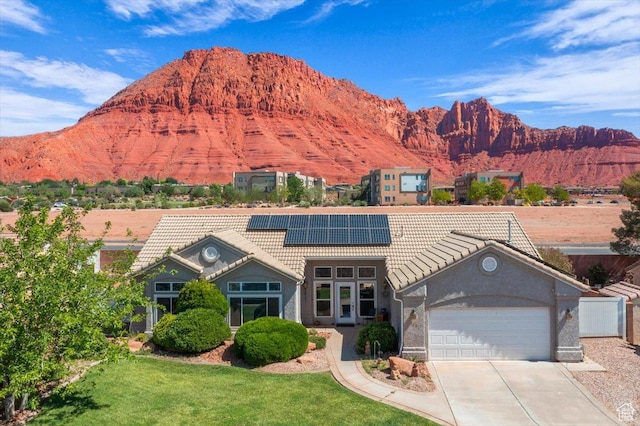 329 E 20 S, Ivins, UT 84738 - view of front of home with a tile roof, solar panels, a garage, a mountain view, and concrete driveway