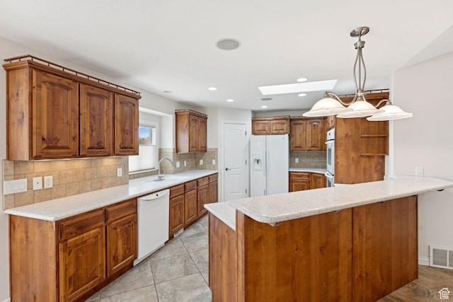 2828 W Gentile St, Layton, UT 84041 - kitchen featuring white appliances, a skylight, a peninsula, brown cabinetry, and light countertops