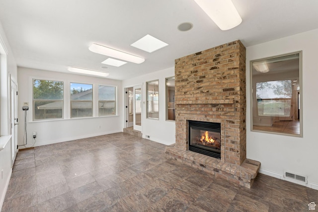 2828 W Gentile St, Layton, UT 84041 - unfurnished living room with a brick fireplace, stone finish flooring, and a skylight