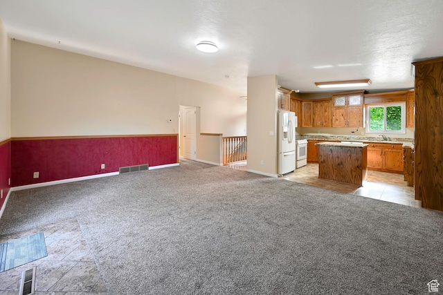421 S 90 W, Richmond, UT 84333 - kitchen with white appliances, open floor plan, a center island, light colored carpet, and brown cabinets