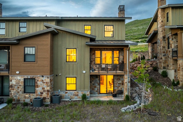 11721 N Shoreline Dr, Hideout, UT 84036 - rear view of property featuring stone siding, a chimney, board and batten siding, a standing seam roof, and a balcony