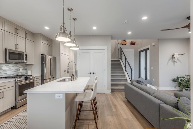 11721 N Shoreline Dr, Hideout, UT 84036 - kitchen with appliances with stainless steel finishes, light wood finished floors, a kitchen island with sink, tasteful backsplash, and recessed lighting
