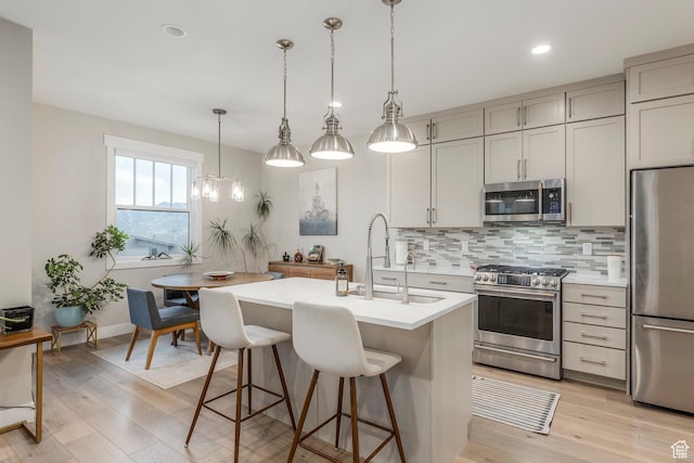11721 N Shoreline Dr, Hideout, UT 84036 - kitchen with stainless steel appliances, backsplash, light countertops, light wood-type flooring, and a breakfast bar area