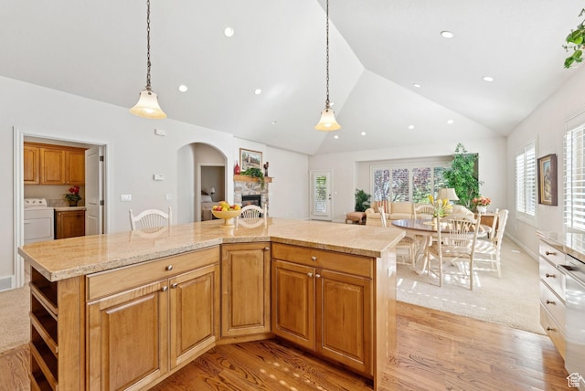 1369 E Farm Dr, Murray, UT 84117 - kitchen with washer / clothes dryer, vaulted ceiling, a fireplace, light wood-type flooring, and arched walkways